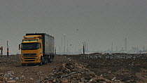 Lorry driving across a landfill site with a gas flare in the background, Pitsea, Essex, England, UK, November 2011.