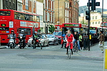 Cyclist and motor cyclist pulling away from traffic light during the rush hour, Angel, London Borough of Islington, England, UK, May 2009