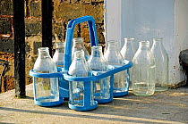 Emply glass reusable milk bottles in crate on doorstep, Highbury, London Borough of Islington England UK