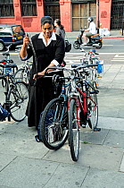 Female cyclist unlocking her bicycle from bike rack, Highbury Corner, London Borough of Islington, England UK, August 2008