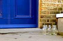 Five empty glass milk bottles on doorstep, Highbury, London Borough of Islington, England, UK