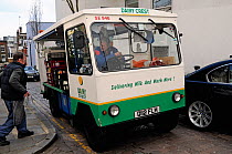 Electric milk float with milkman delivering milk, Hampstead London Borough of Camden, England UK, April 2009