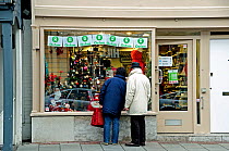 Couple outside Oxfam Shop, just before Christmas, Highgate Village London, England, UK, December 2009