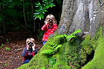 Young brother and sister bird watching in woodland in summer, Norfolk. July 2012. Model Released Model released.