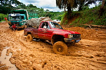 Vehicles stuck in deep mud - the onset of the rainy season deteriorates dirt roads making transport difficult, Cameroon, August 2009.