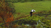 Joe Cornish walking through a fire-damaged landscape in the rain whilst on assignment for 2020vision, near Lochinver, Coigach / Assynt Scottish Wildlife Trust, Sutherland, Highlands, Scotland, UK, Jun...