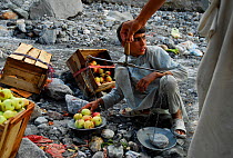 Fruit peddlers weighing apples for sale alongside the Karakoram Highway, Pakistan, July 2007.