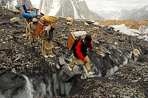 Three Balti porters crossing a crevasse on the Baltoro Glacier, Central Karakoram National Park, Pakistan, June 2007.
