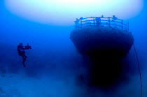 Wreck of the cargo ship 'Iouna'. Cameraman and ships stern with navigation light still attached on rail. Wrecked between 1912-1918. Sharmo reef, Yanbu, Saudi Arabia, July 2010