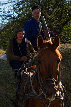 Farmer couple on a carriage drawn by a chestnut horse, loaded with hay in the village of Isverna. Geoparcul Platoul Mehedinti, Romania, October 2012