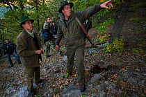 Romanian forester pointing out stand to a fellow hunter during a driving hunt for Wild boar (Sus scrofa) in the forest area outside the village of Mehadia, Caras Severin, Romania, October 2012
