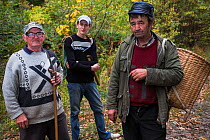 Three Romanian men returning from picking edible tree mushrooms from Common beech forest close to Baile Herculane, Caras Severin, Carpathians, Romania, October 2012