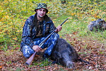 Young Romanian hunter posing with his first Wild boar (Sus scrofa) that he shot during a driving hunt in the forest area outside the village of Mehadia, Caras Severin, Romania, October 2012