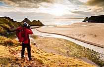 Man taking a photograph of Three Cliffs Bay, Gower, Swansea, Wales. January 2013. Model released.