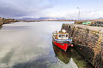View over Roundstone Harbour, with fishing boat moored to the quay, Connemara, Republic of Ireland, March 2013.