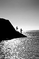 Two men fishing, Lansallos Cove, Cornwall, England, October 2012. Model released.