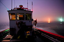 West coast rock lobster (Jasus lalandii) fishing boat (James Archer) leaves the Saldhana Bay harbour before the break of dawn. The lights of the town and the lighthouse flash on the horizon. Saldhana...