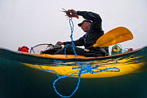 Man recreational fishing from a sea kayak for West coast rock lobster (Jasus lalandii). Kommetjie, Western Cape, South Africa