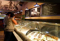 Customers look at the deli, fresh and frozen seafood display inlcuding West coast rock lobster (Jasus lalandii) in the restaurant, Cape Town Fish Market, restaurant, Victoria and Alfred Waterfront, Ca...