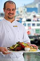 West coast rock lobster (Jasus lalandii) chef with plate of  cooked lobster at OYO restaurant, Victoria and Alfred Waterfront, Cape Town, South Africa.