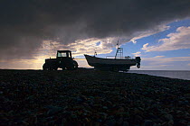 Tractor towing boat, on Cley beach, with stormy clouds, Norfolk, May 2013
