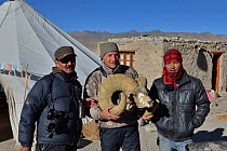 Photographer Eric Dragesco holding Tibetan Argali Skull, (Ovis ammon hodgsoni), with guides, ChangThang, Tso Kar Lake, at altitude of 4600m, Ladakh, India, October 2012