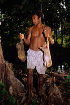 Hunter with Eastern common cuscuses (Phalanger intercastellanus) Fergusson island, Papua New Guinea.