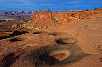 Pot holes in sandstone and Green River Canyon, Canyonlands National Park, Utah, USA December 2012