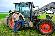 Christian Schmitt, Christian Schmitt, a common hamster friendly farmer, in front of his tractor in a wheat field, Elsenheim, Alsace, France, May 2013