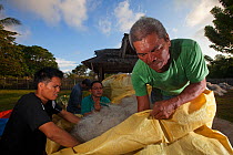 Project Seahorse foundation staff with two tons of discarded plastic fishing nets ready to be shipped out and recycled into carpet material, Jao Island, Danajon Bank, Central Visayas, Philippines, Apr...