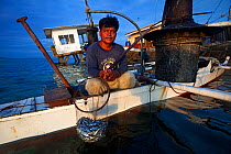 Lantern fishermen with catch in front of a house about to fall into the sea, Bilang Bilangang Island, Danajon Bank, Central Visayas, Philippines, April 2013