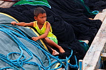 Boy amongst fishing nets, Bilang Bilangang Island, Danajon Bank, Central Visayas, Philippines, April 2013