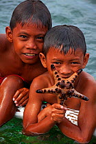 Children with a Chocolate Chips Sea Star (Protoreaster nodosus), Bilang Bilangang Island, Danajon Bank, Central Visayas, Philippines, April 2013