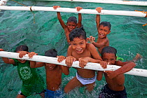 Children hanging off outrigger of boat, Bilang Bilangang Island, Danajon Bank, Central Visayas, Philippines, April 2013