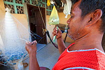 Man repairing plastic fishing nets, Batasan Island, Danajon Bank, Central Visayas, Philippines, April 2013