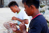 Men repairing nylon fishing nets, Batasan Island, Danajon Bank, Central Visayas, Philippines, April 2013