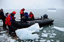 Tourists disembarking from zodiac boat with Antarctic cruise liner 'MV Ushuaia' in the background Antarctic Peninsula, Antarctica