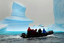 Tourists on a zodiac going past icebergs in Iceberg Alley, Pleneau Island, Antarctica