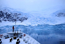View of Antarctic Peninsula from 'MV Ushuaia' foredeck, with tourist looking out onto the landscape. Antarctica
