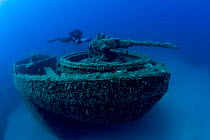 Diver exploring with scooter the bow with machine gun of the LST 349, a British Landing Ship Tank sunk on Febbruary 1944, Ponza Island, Italy, Tyrrhenian Sea, Mediterranean