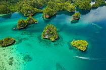 Limestone Islands of Kabui Bay, near the East end of the Passage between Gam and Waigeo. Waigeo Island at top, with local boat heading for the Passage. Raja Ampat Islands, West Papua, Indonesia. Octob...