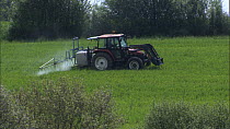 Wide shot of a tractor spraying pesticide or fertiliser on a field, France, April.