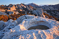 An ice filled crater with view of the sculptured granite boulders strewn across landscape of Silent City of Rocks National Preserve. Idaho. April 2013