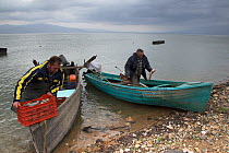Fishermen arriving back at the shore after a fishing trip. Lake Kerkini, Greece. February 2013