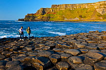 Tourists with compact cameras walking along Giant's Causeway, UNESCO World Heritage Site. Antrim County, Northern Ireland, Europe. June 2011