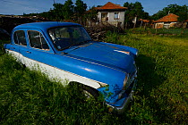 Blue rusting car in front of house, Dolni Glavanak, Eastern Rhodope Mountains, Bulgaria, May 2013.