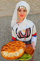 Young woman in Balkan dress offering bread and honey at the celebration of the opening of a new Tahini-production factory in Kondovo village, Eastern Rhodope Mountains, Bulgaria, May 2013.