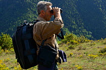 Vlado Peikov, hunting area manager looking through binoculars, Deven area, Western Rhodope Mountains, Bulgaria, May 2013.