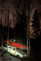 Old abandoned cars stacked on atop the other in 'car graveyard' at night, Bastnas, Sweden April