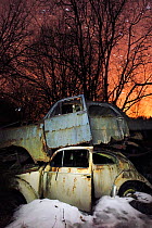 Old abandoned cars stacked on atop the other in 'car graveyard' at night, Bastnas, Sweden April